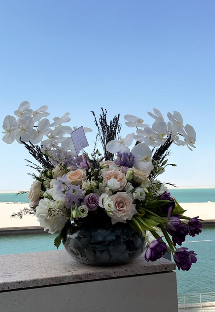 Orchids, purple tulips and roses in a fishbowl