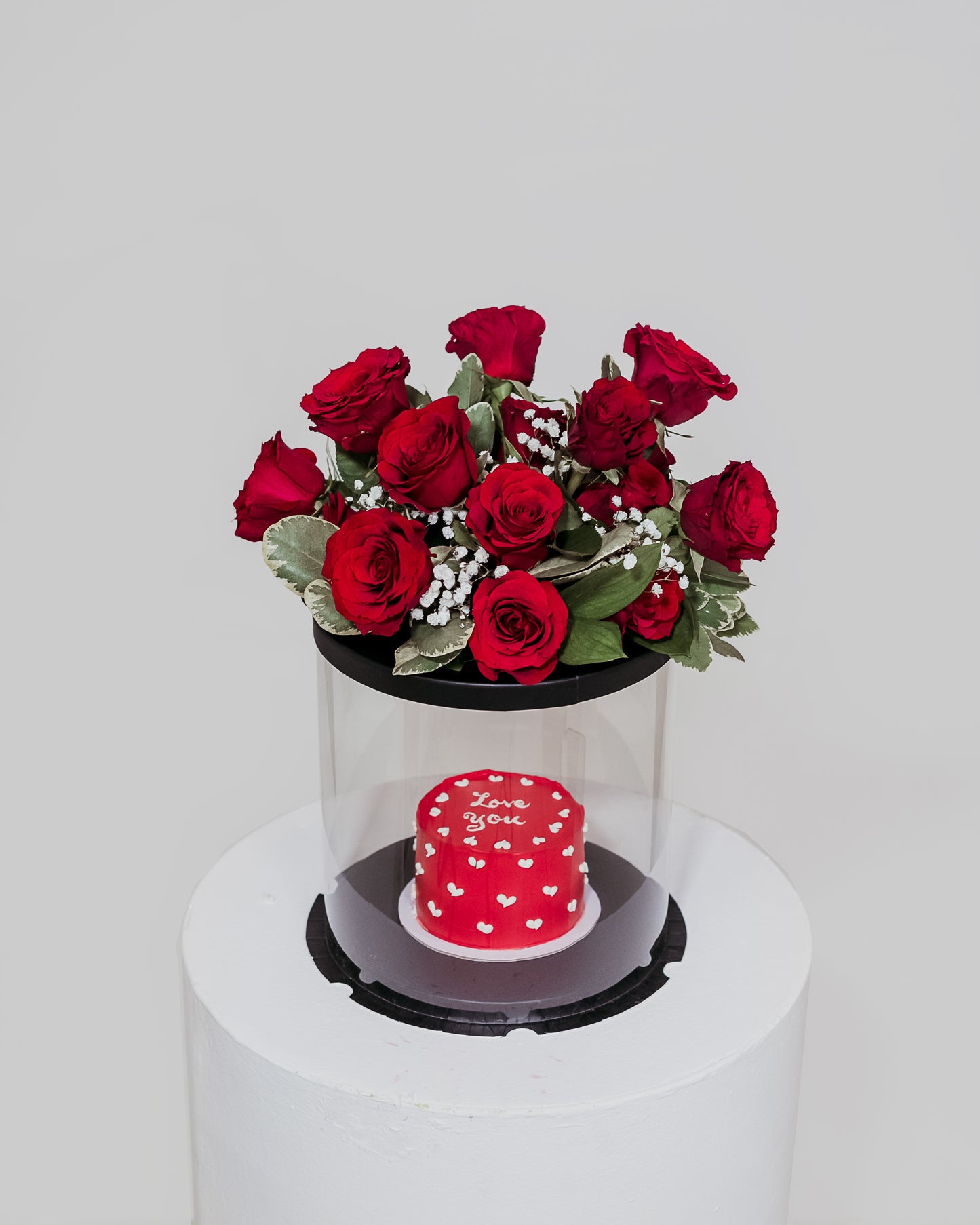 A delectable red Valentine's cake presented in a box, accompanied by a beautiful arrangement of flowers, a sweet and romantic gift for Valentine's Day.