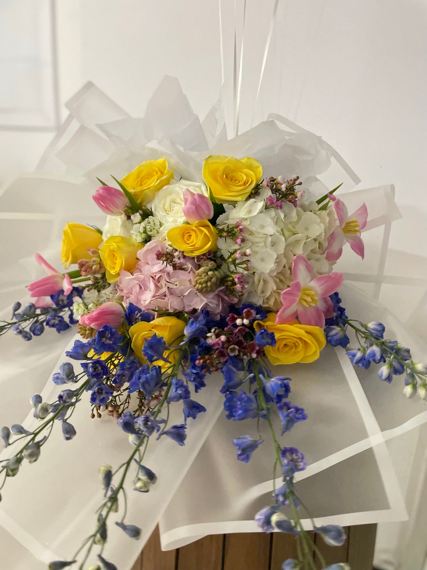 Blue delphinium with yellow roses in a vibrant coloured bouquet