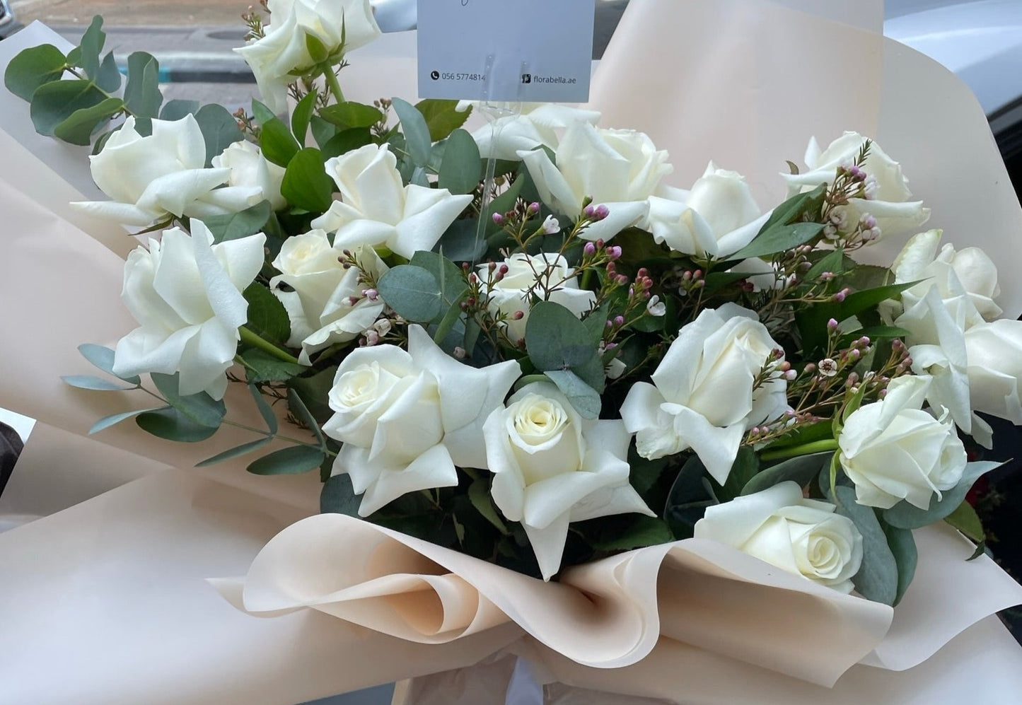 white roses in a bouquet with beige wrapping