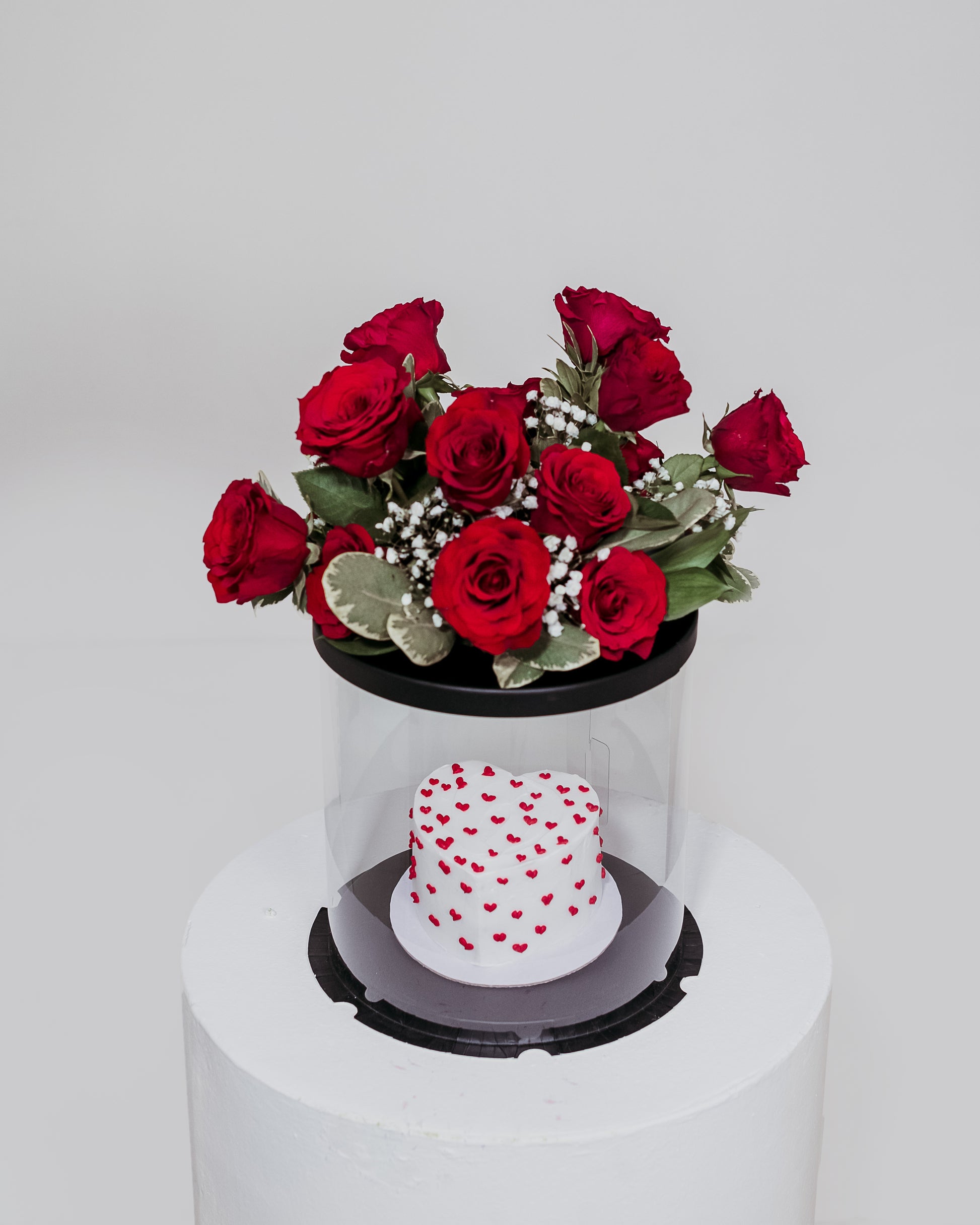 A delightful white Valentine's cake beautifully packaged in a box, accompanied by a lovely arrangement of flowers, a sweet and elegant Valentine's Day present.