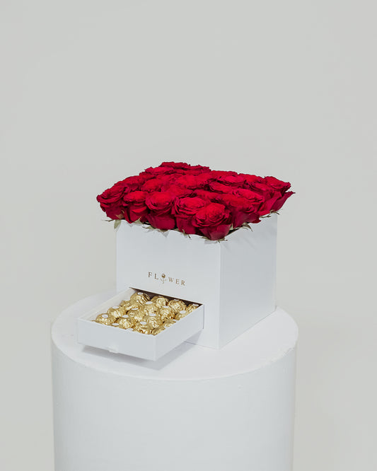 An elegant white box filled with beautiful red roses, complemented by a drawer filled with delicious Ferrero Rocher chocolates, a charming Valentine's Day present.