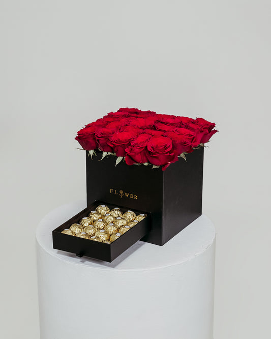 A black box filled with vibrant red roses, accompanied by a drawer containing indulgent Ferrero Rocher chocolates, an exquisite Valentine's Day gift.
