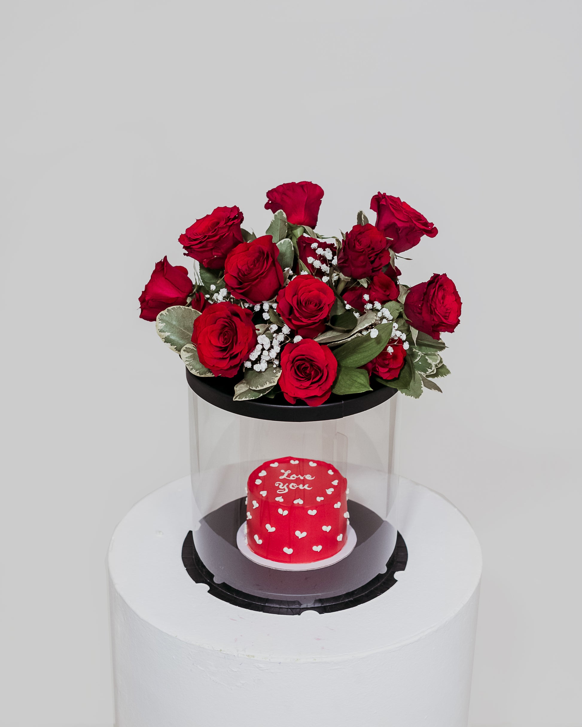 A delectable red Valentine's cake presented in a box, accompanied by a beautiful arrangement of flowers, a sweet and romantic gift for Valentine's Day.