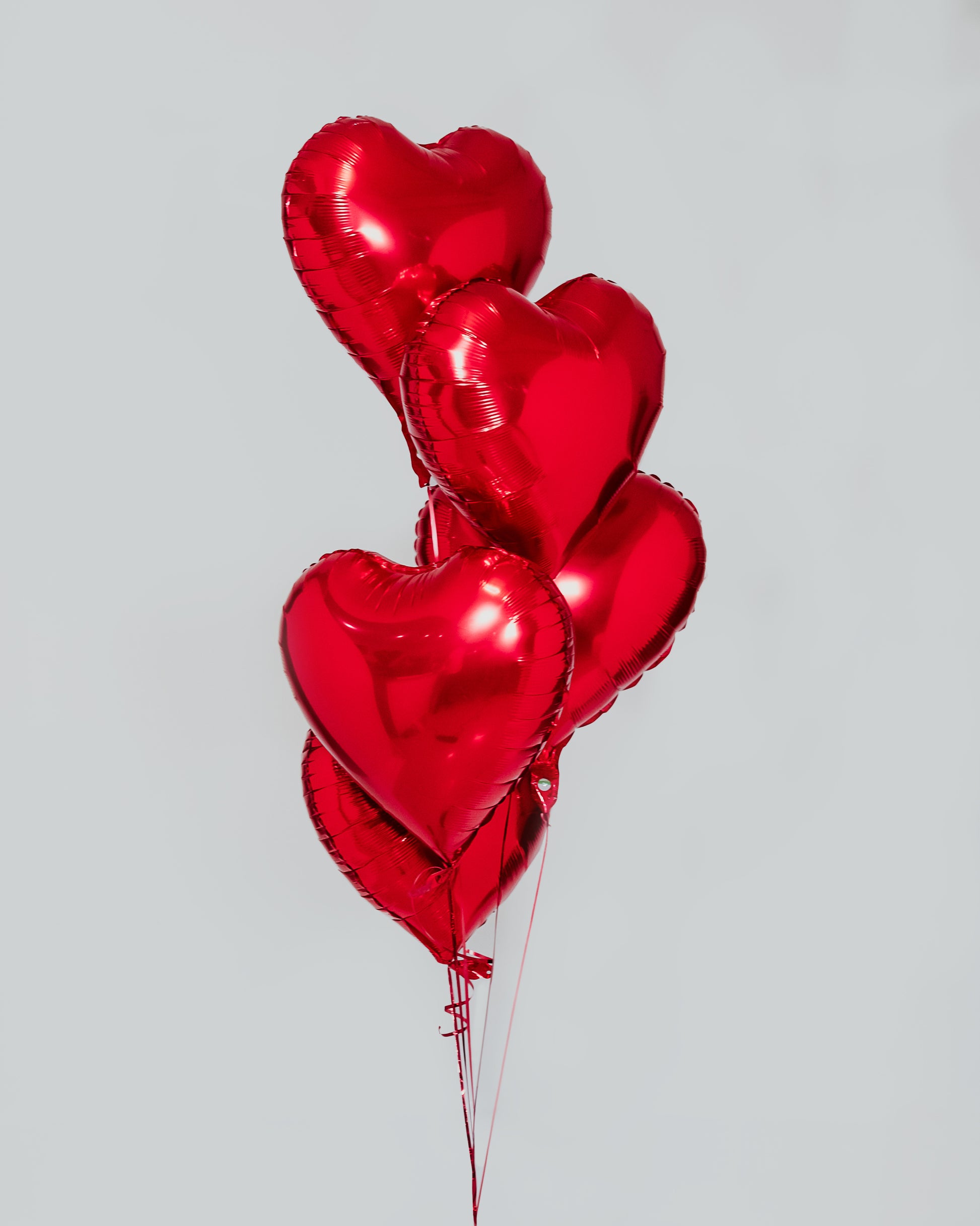 Five heart-shaped foil balloons, adding a festive touch to Valentine's Day.